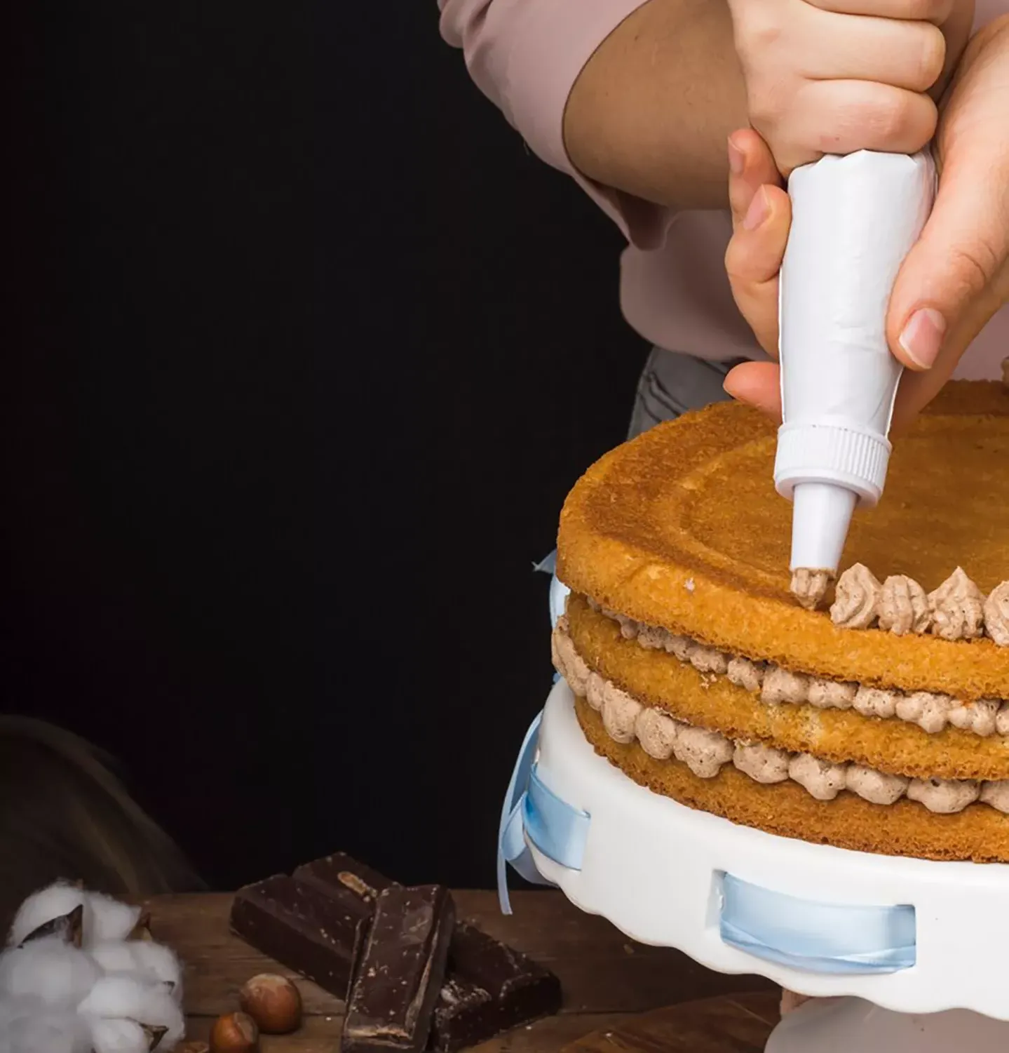 Pastelero poniendo crema sobre un pastel con una manga pastelera