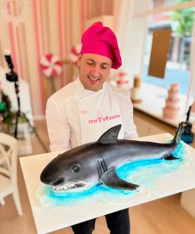 Persona sujetando una tarta con forma de tiburón blanco